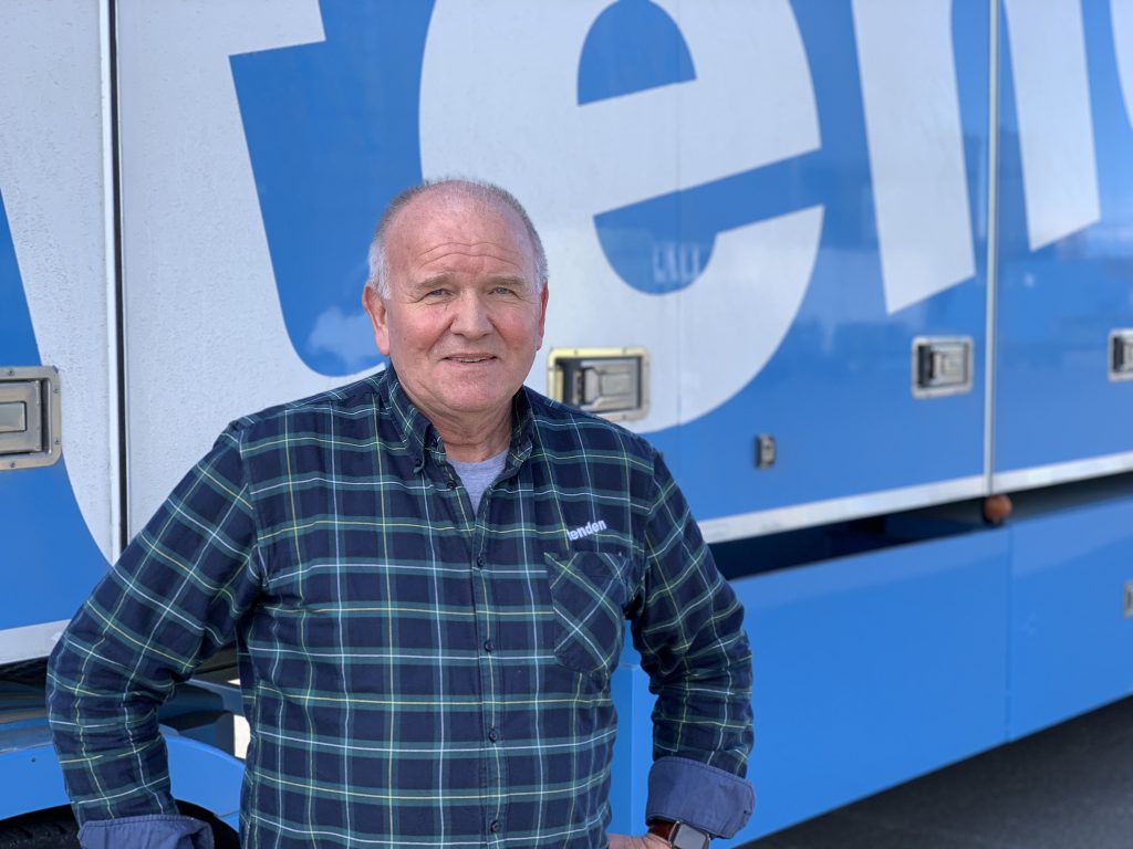Rolf Olav Tenden står foran en stor Tenden-bil
